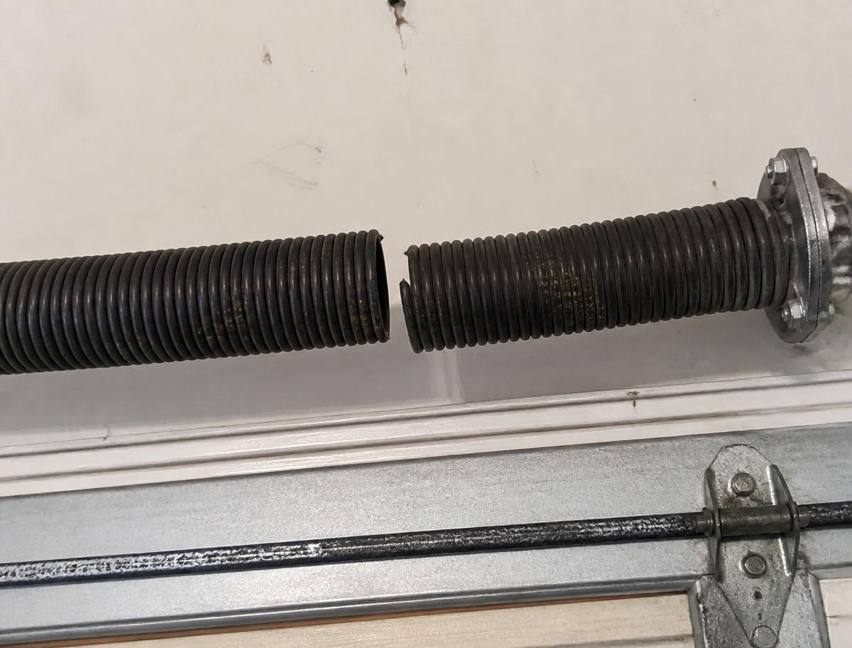 Snapped garage door torsion spring with a visible gap in the coil